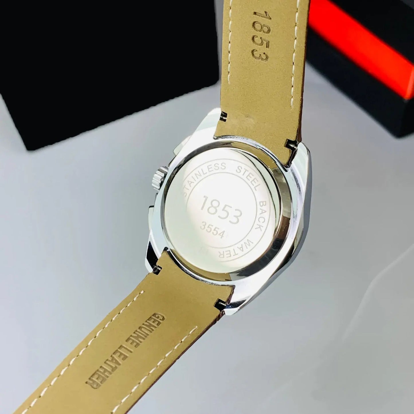 Watch with beige leather strap and visible brand name on a light gray background